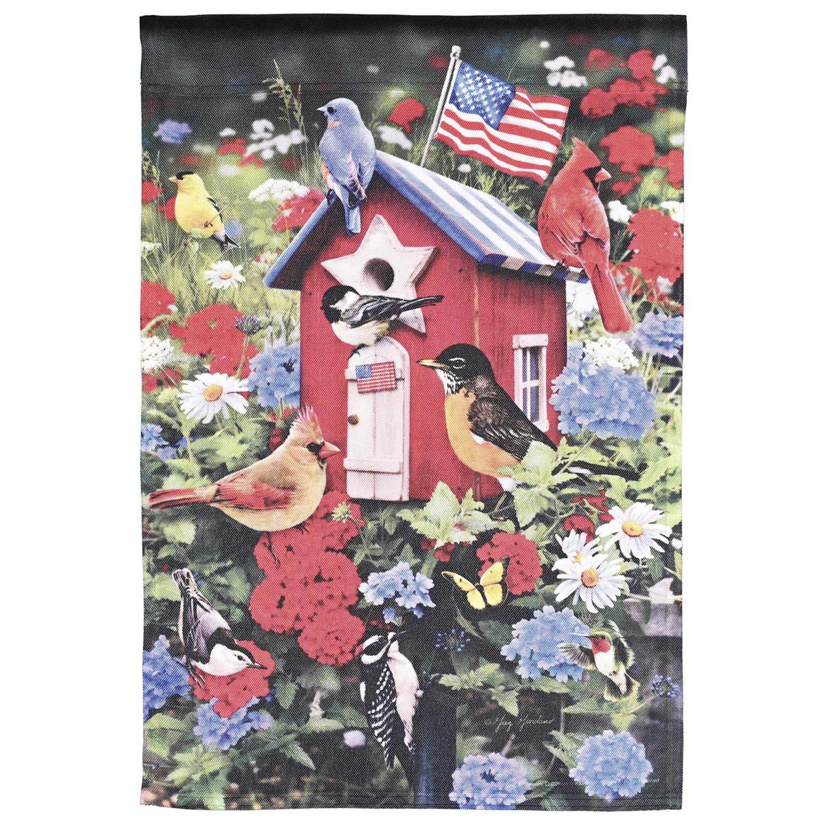13x18 printed garden flag showing a red, white and blue Patriotic Birdhouse with perched birds, displayed on a yard flag stand amid garden greenery.