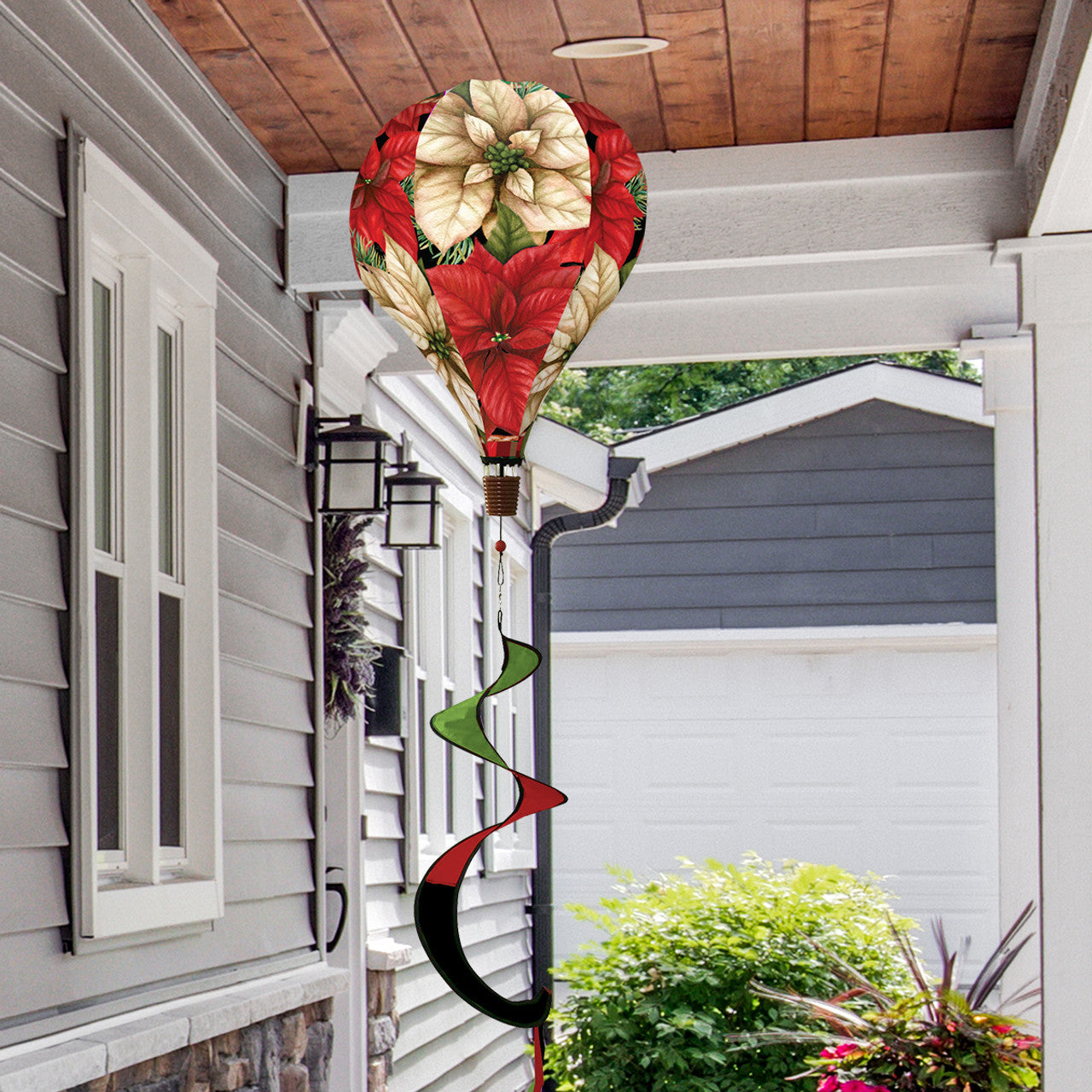 Hot air balloon spinner with red poinsettias, holly, and greenery, made of weather-resistant polyester for elegant, festive holiday outdoor garden décor.