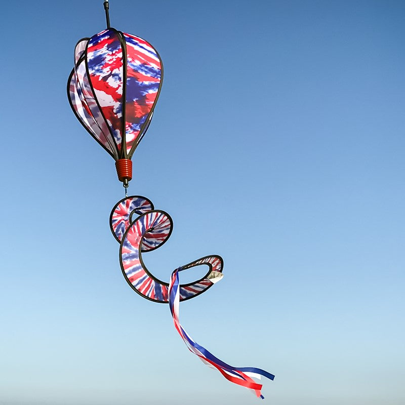 Red, White, and Blue Tie Dye 6-Panel Hot Air Balloon soaring outdoors, showcasing its bold tie-dye pattern against a clear, open sky.